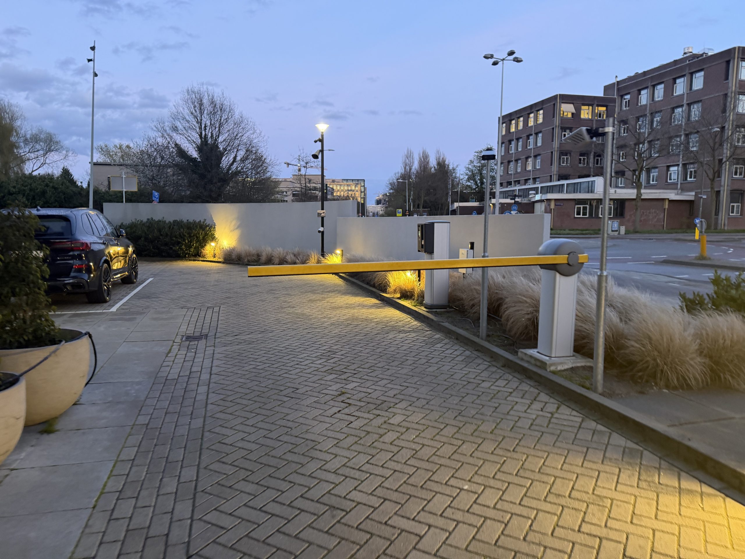 Parkeerterrein met slagboom bij een hotel in Amsterdam in de schemering, beveiligd met camerabewaking en luidspreker