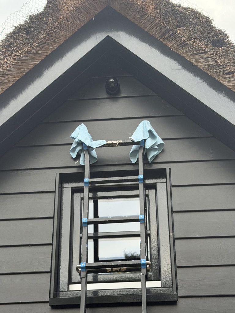 Ladder met doeken over de sporten tegen een geverfde gevel
