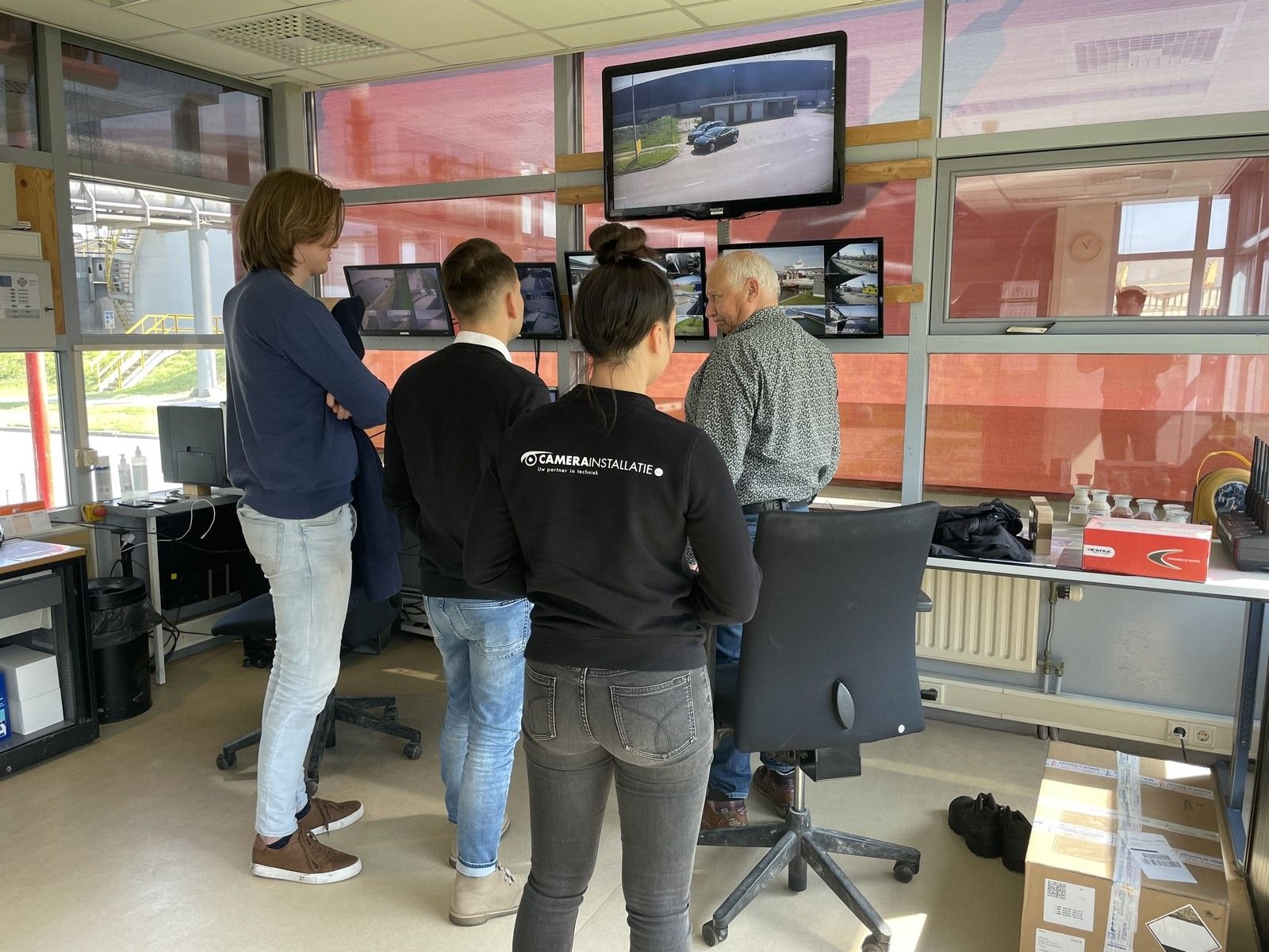 Klant volgt de camerabeelden in de meekijkruimte van een industrieel terrein