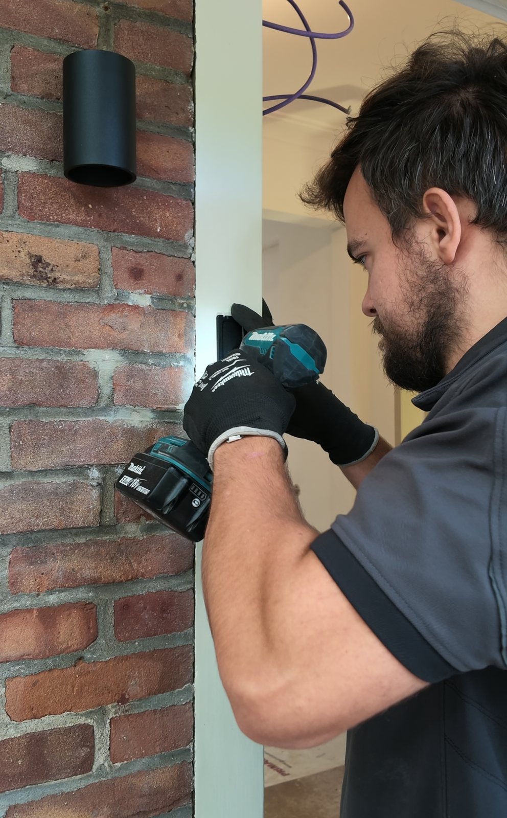 Monteur van CameraInstallatie boort het bevestigingsgat voor een videodeurbel naast de voordeur