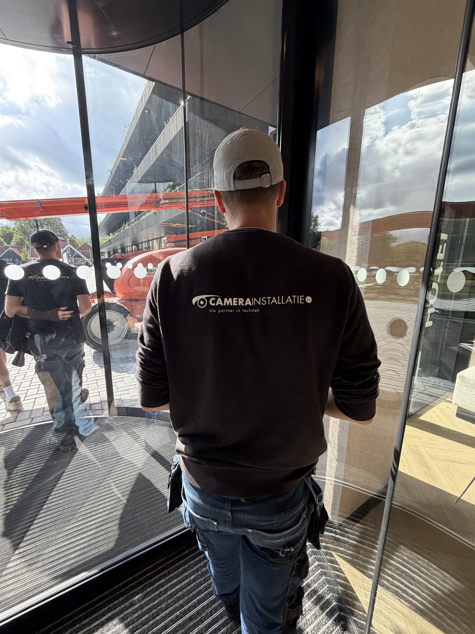 Monteur van CameraInstallatie.nl in bedrijfskleding bij de entree van een bedrijfspand