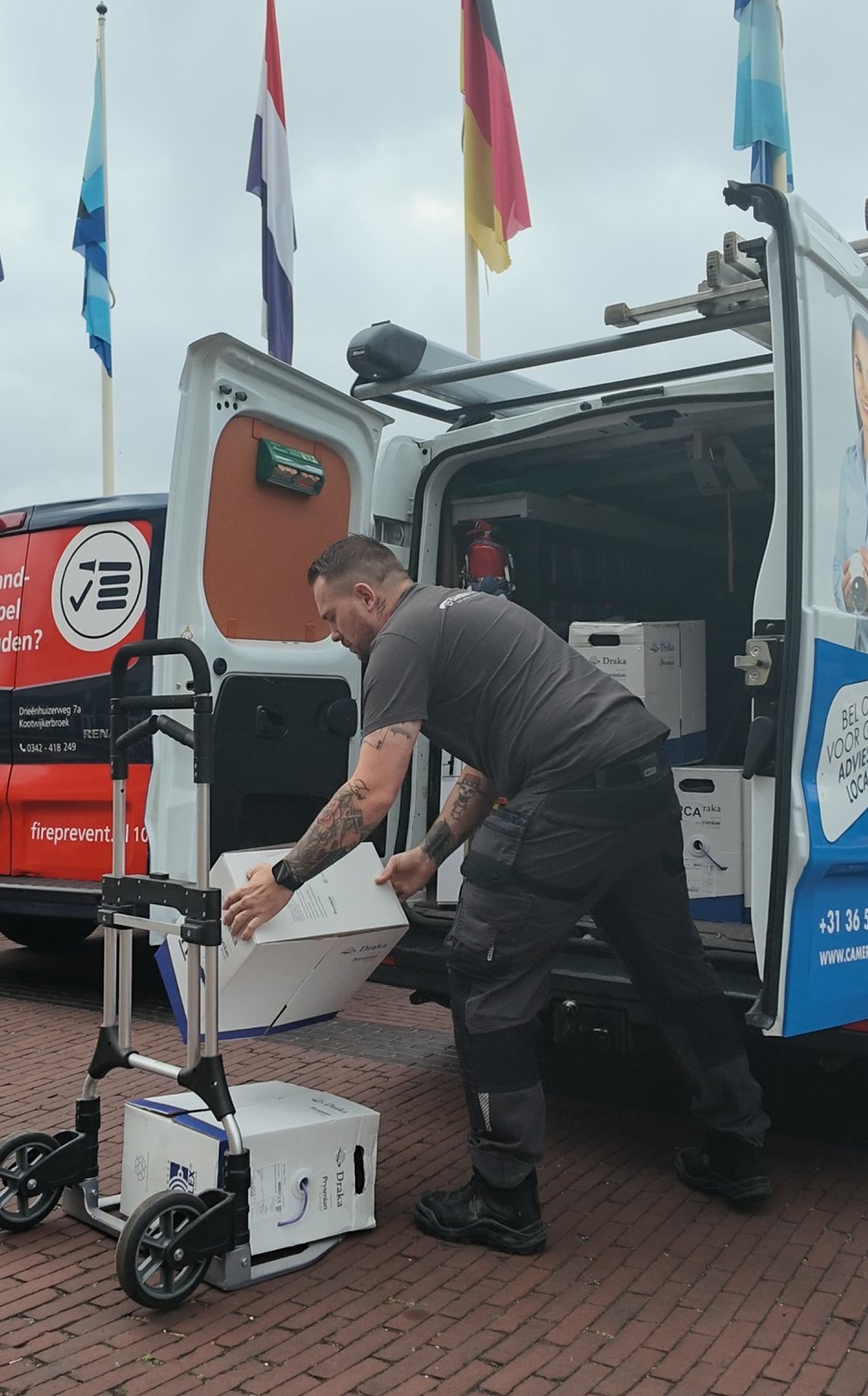 Monteur laadt dozen netwerkkabel uit de bedrijfsbus