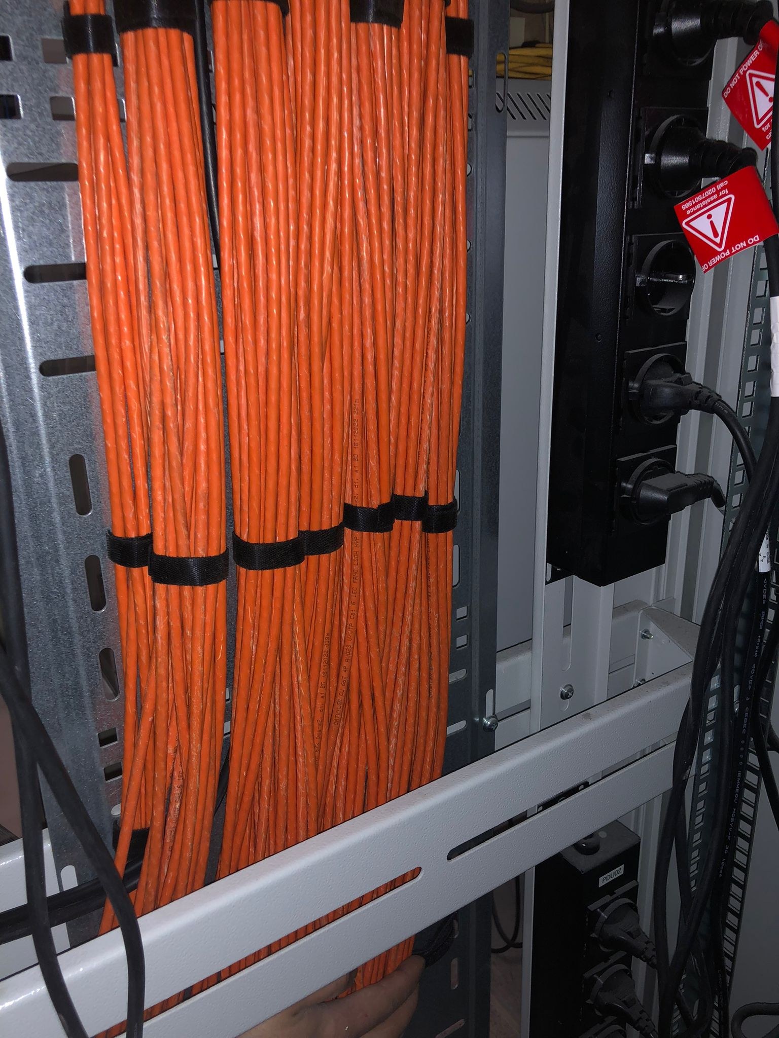 Bundel oranje gecertificeerde cat6-netwerkkabels netjes weggewerkt in een patchkast