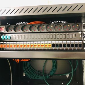 Afgemonteerde patchkast met stroomverdeling en genummerde netwerkkabels