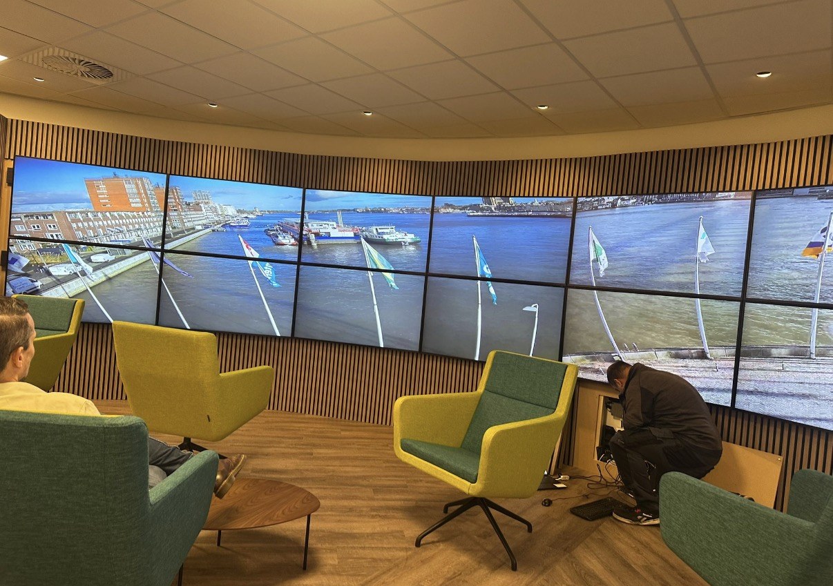 Monteur van CameraInstallatie sluit de apparatuur aan onder de gebogen videowall in de vergaderzaal