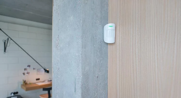 Witte Ajax MotionProtect bewegingsmelder, strak gemonteerd in een modern bedrijfspand