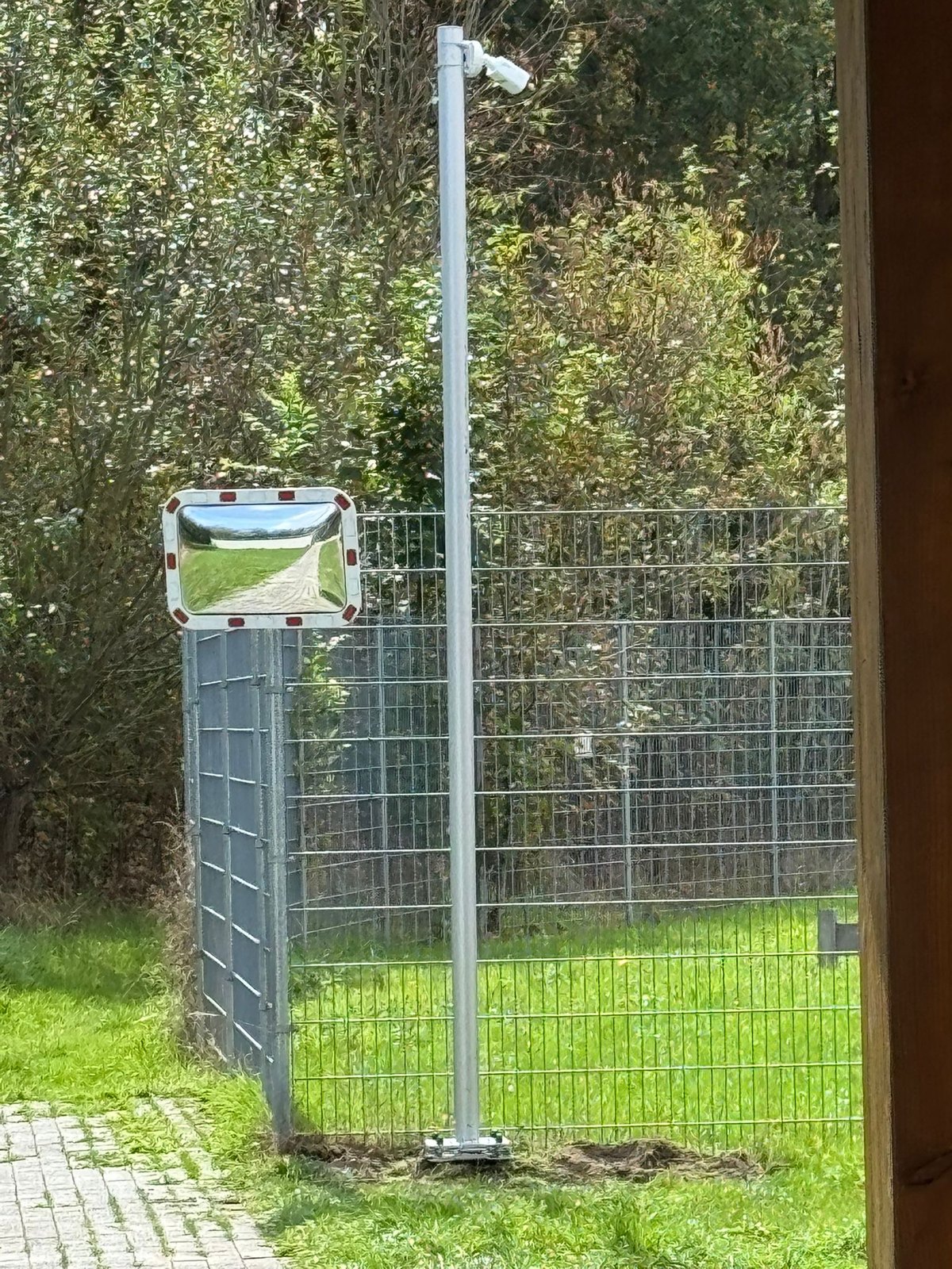 Beveiligingscamera op een verzinkte paal bij het hekwerk aan de toegangsweg van een bedrijfsterrein