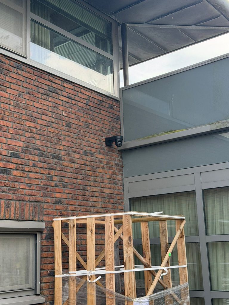 Zwarte beveiligingscamera onder de overkapping aan de achtergevel van een woning
