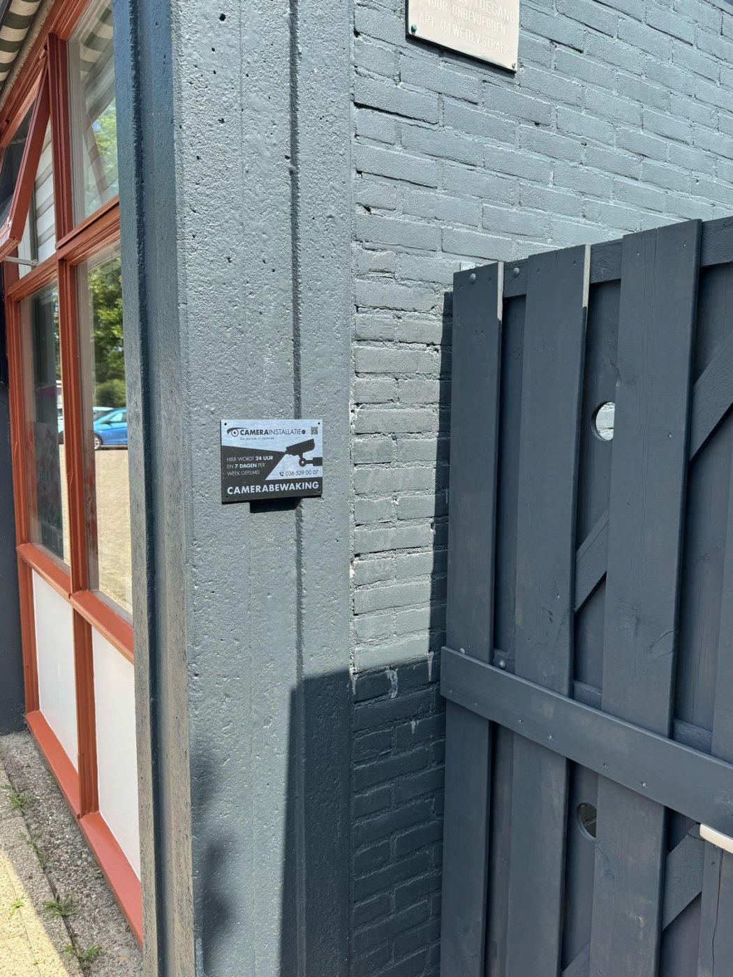 Bord camerabewaking op de zijgevel bij het toegangshek