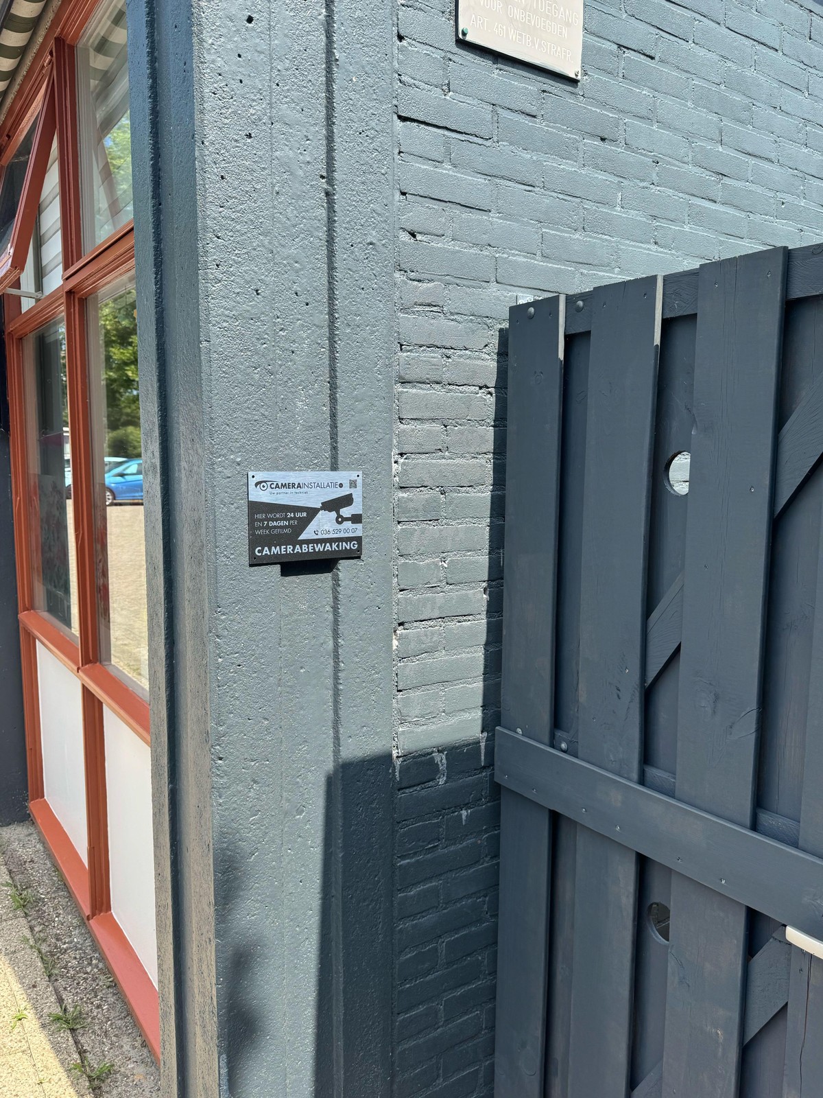 Bord camerabewaking op de zijgevel bij het toegangshek