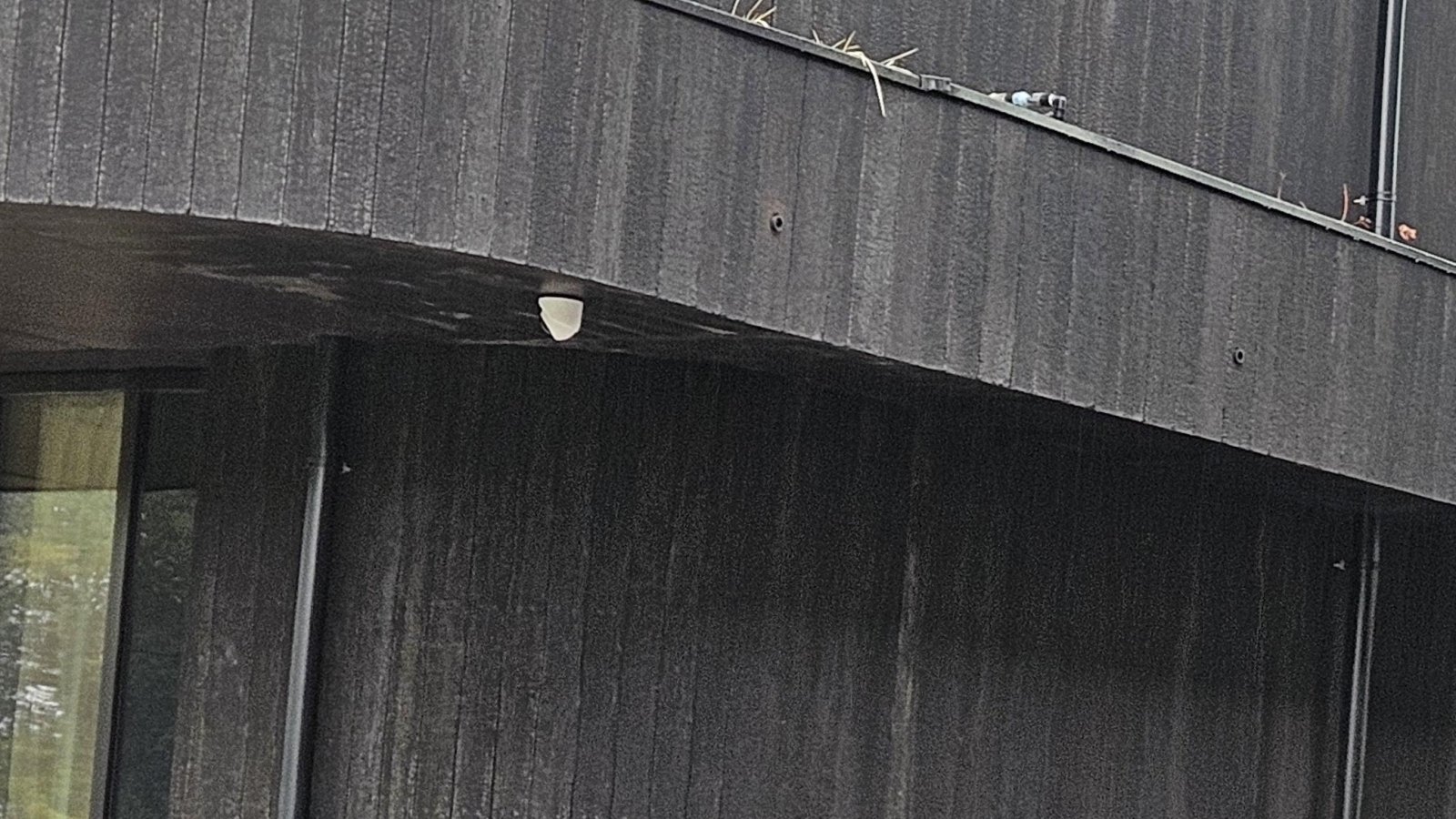 Camera onder de uitkragende gevel met zicht op de entree van het hotel