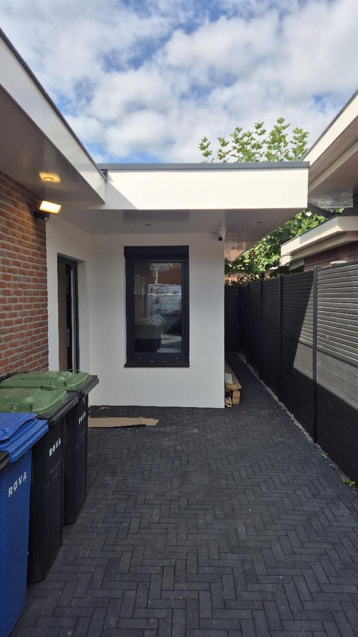 Camera onder de overstek met zicht over het zijpad langs de woning
