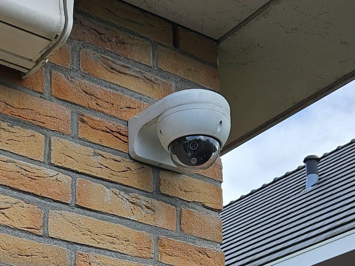 Close-up van de witte dome-camera op de hoek onder de dakrand, zonder zichtbare kabel