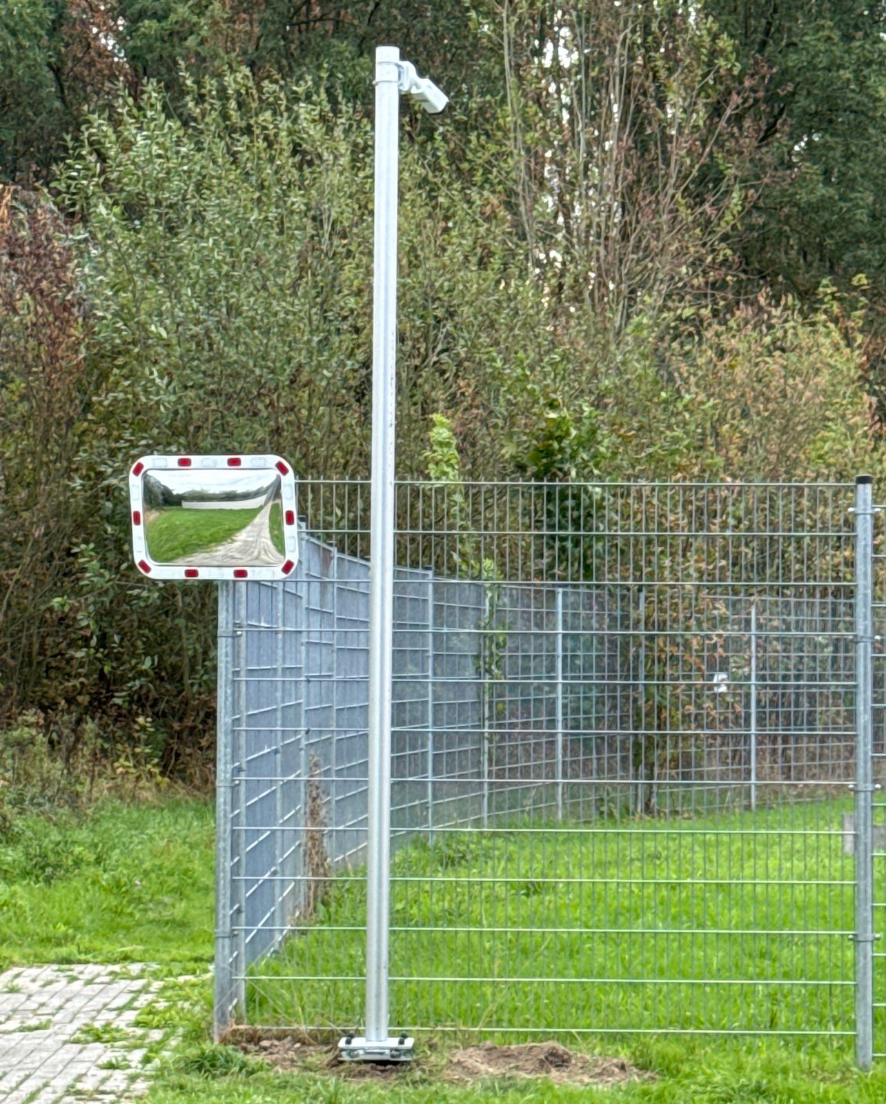 Camera op een verzinkte mast naast een hekwerk bij een toegangsweg