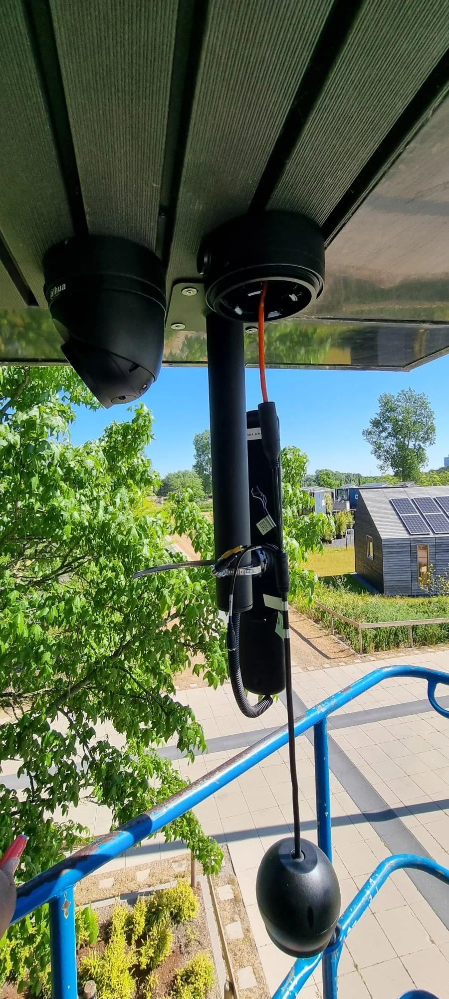Twee zwarte Dahua-camera's gemonteerd onder de dakrand van een gebouw, met een groen buitenterrein op de achtergrond