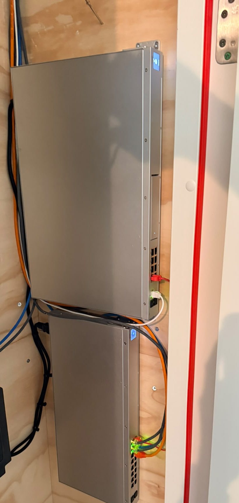 Meterkast met de UniFi Dream Machine boven en de UniFi-switch eronder, kabels netjes langs de wand