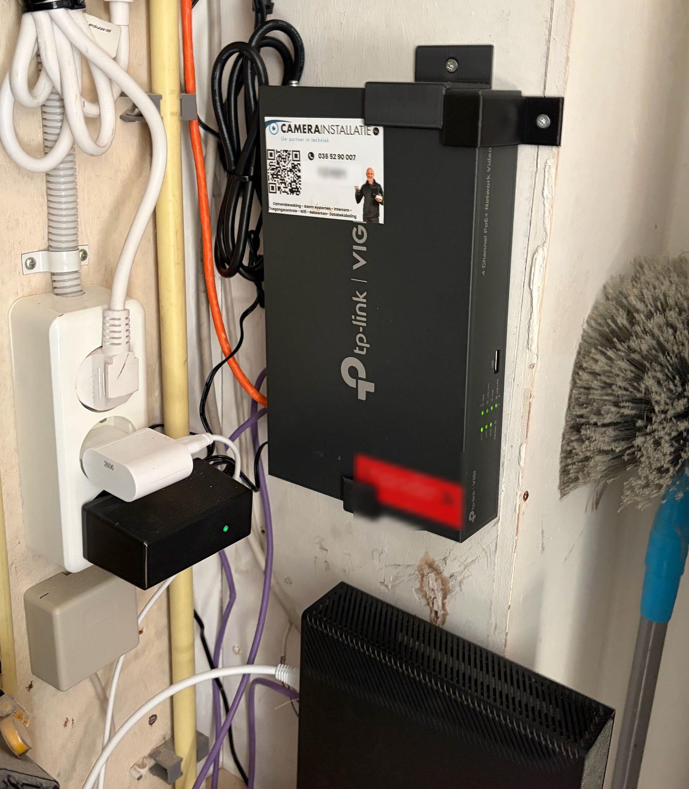 VIGI-recorder met vier PoE-poorten in de kast, vastgezet met zwarte beugels die CameraInstallatie.nl zelf op maat 3D-print