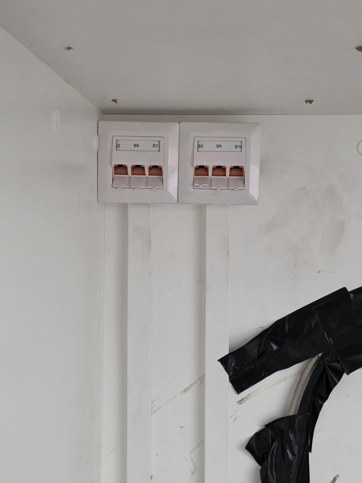 Twee opbouwdozen met elk drie netwerkpoorten boven elkaar aan een witte wand
