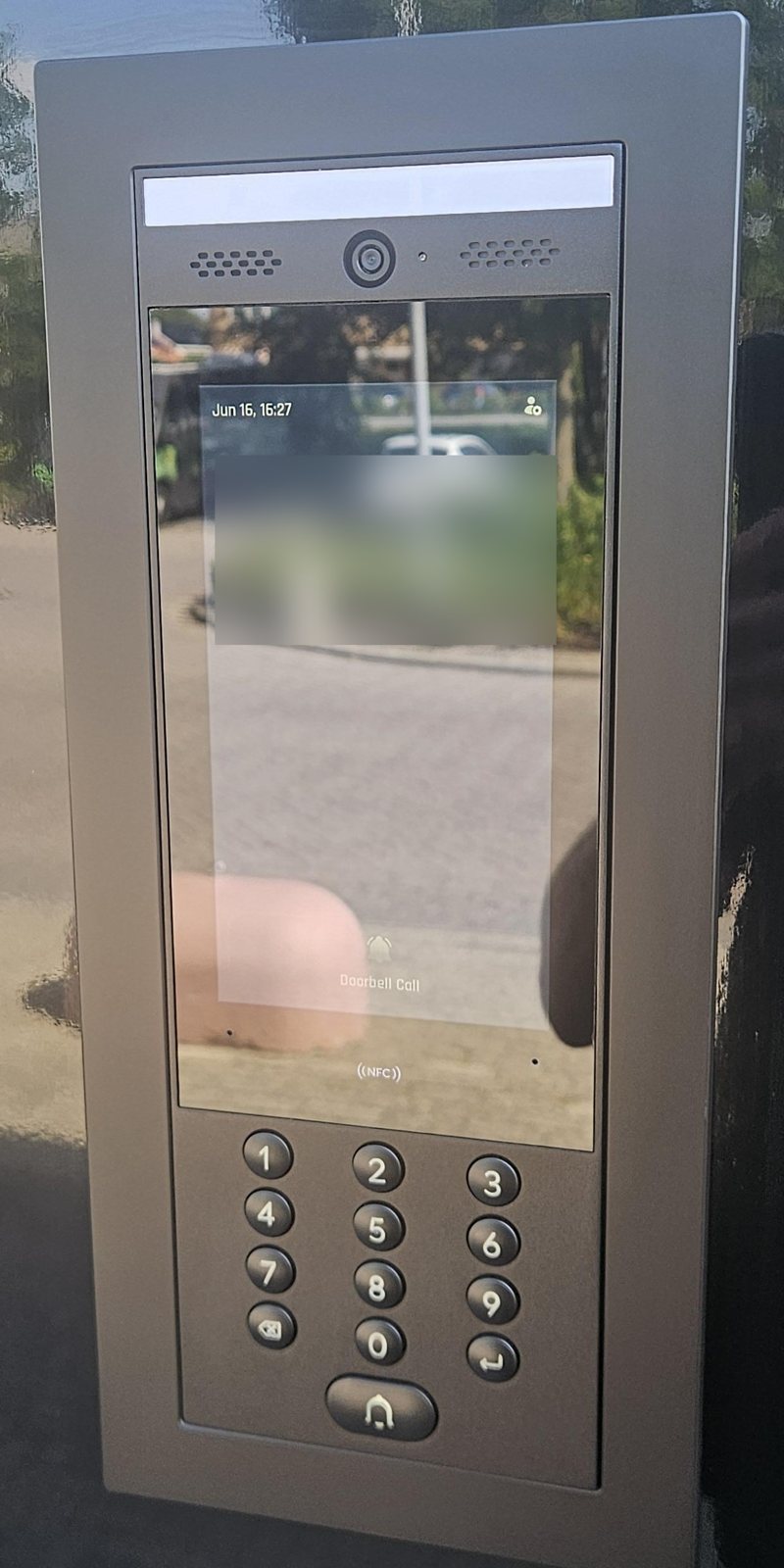 Intercom met groot scherm, camera en cijfertoetsen in een zwart paneel bij de voordeur
