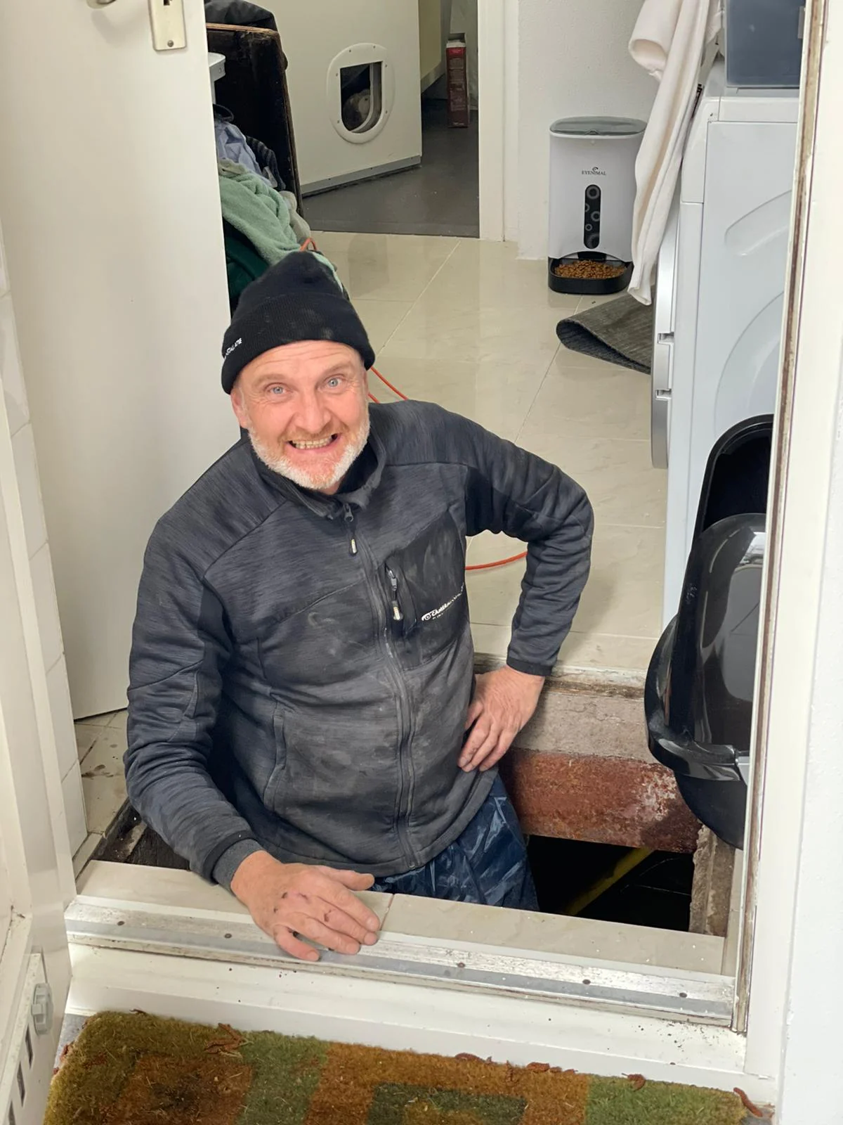 Monteur van CameraInstallatie klimt uit de kruipruimte van een woning na het trekken van kabel