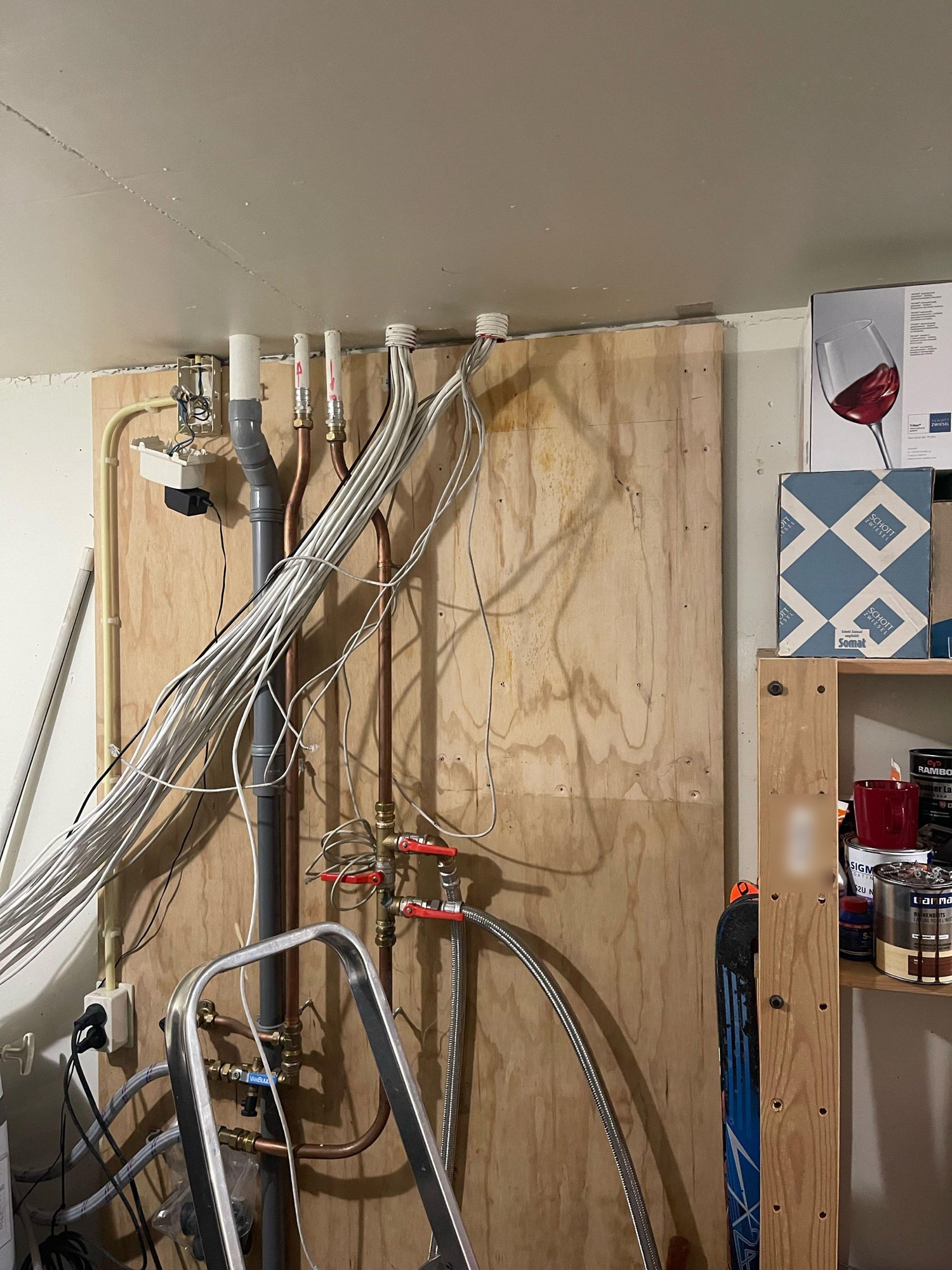 Bundels witte netwerkkabels die los langs de houten wand hangen, voordat het patchrek werd geplaatst