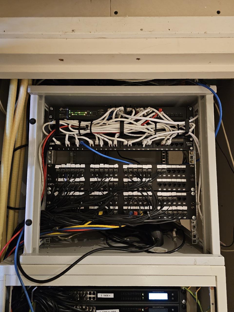 Open patchkast met patchpaneel, witte patchkabels en een switch