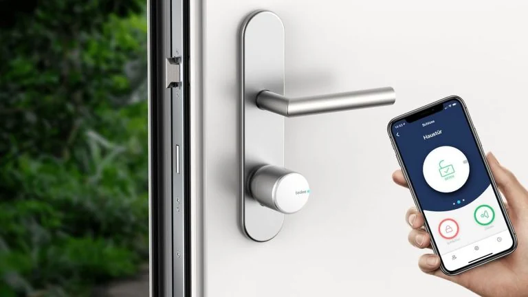 Tedee slim slot op de cilinder aan de binnenkant van een deur, met de app op een telefoon