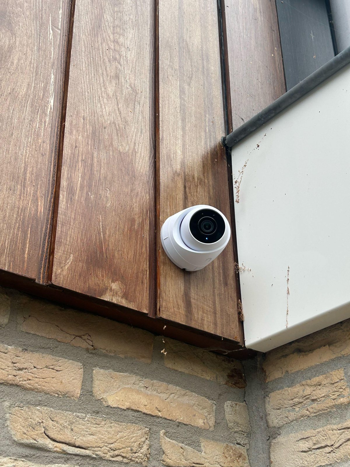 Witte UniFi G5 Turret Ultra op de hoek van de gevel, met zicht op de achtertuin