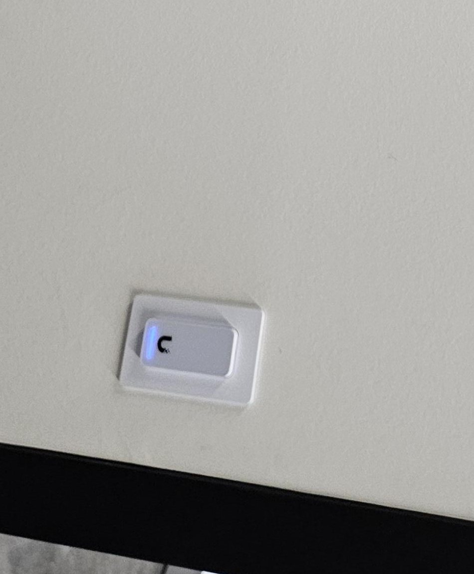 Liggend gemonteerde UniFi-lezer met blauw lampje op een witte wand boven een zwart kozijn