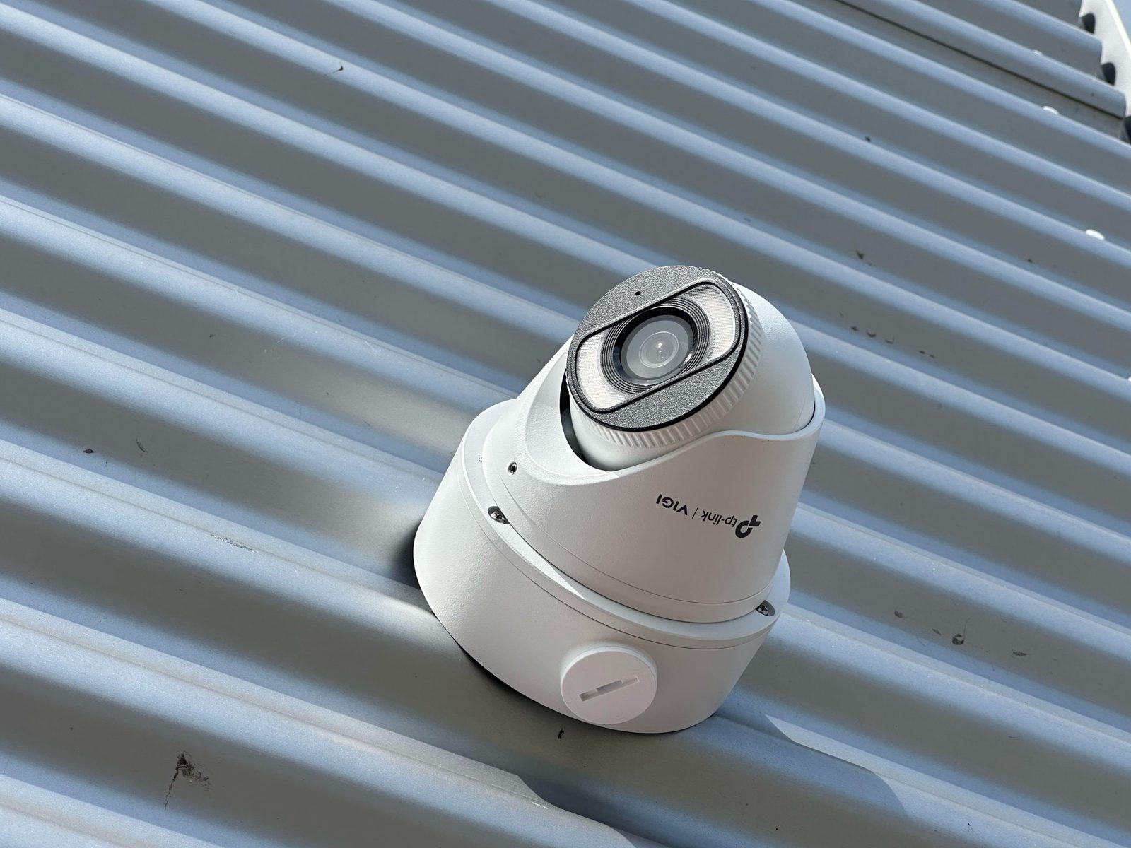 Witte VIGI-camera van 8 megapixel onder de dakrand van het bedrijfspand in Roosendaal, boven een deur