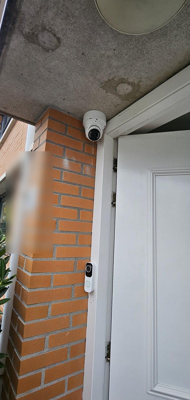 Witte VIGI-camera onder de overkapping bij de entree