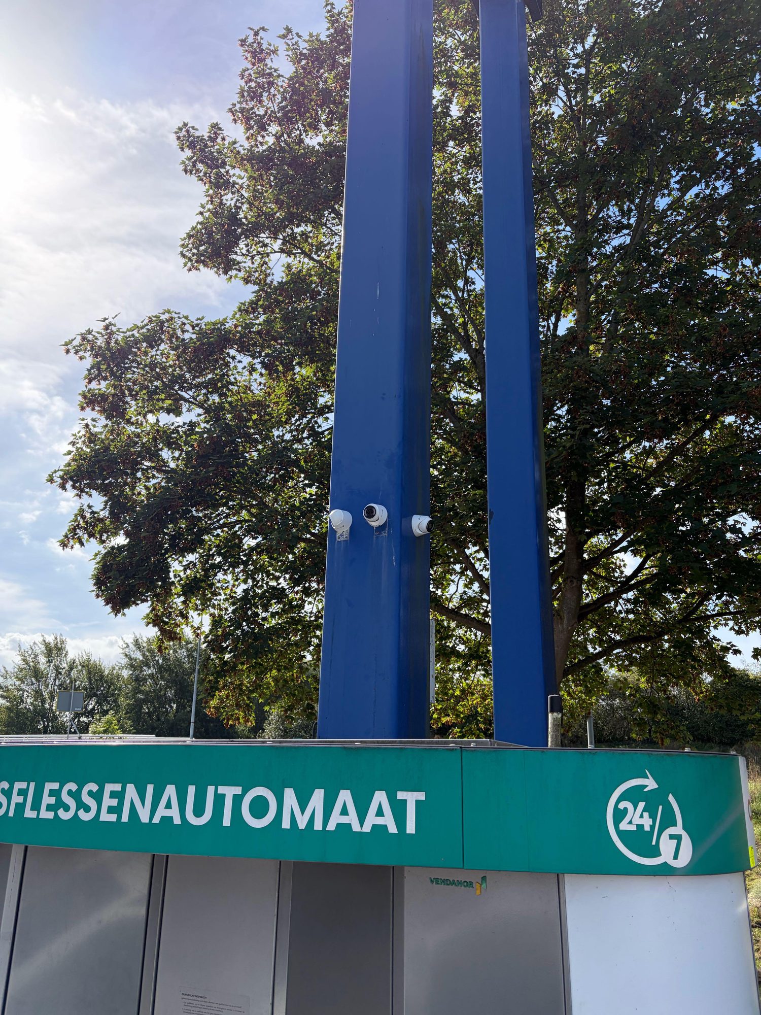 Drie witte VIGI-camera&rsquo;s op een blauwe mast bij het tankstation