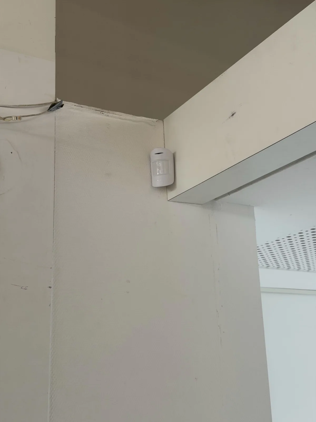 Witte Ajax-bewegingsmelder hoog in de hoek van een witte wand
