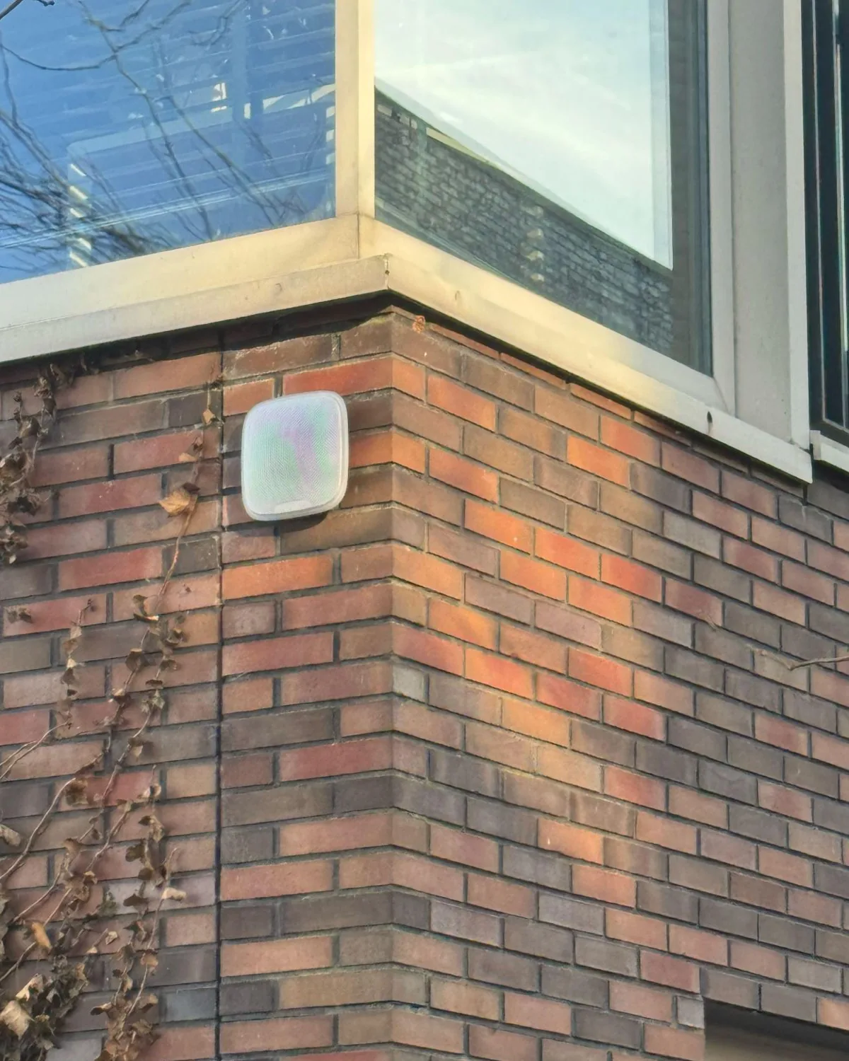 Witte Ajax-buitensirene hoog op de hoek van een bakstenen gevel in Amsterdam