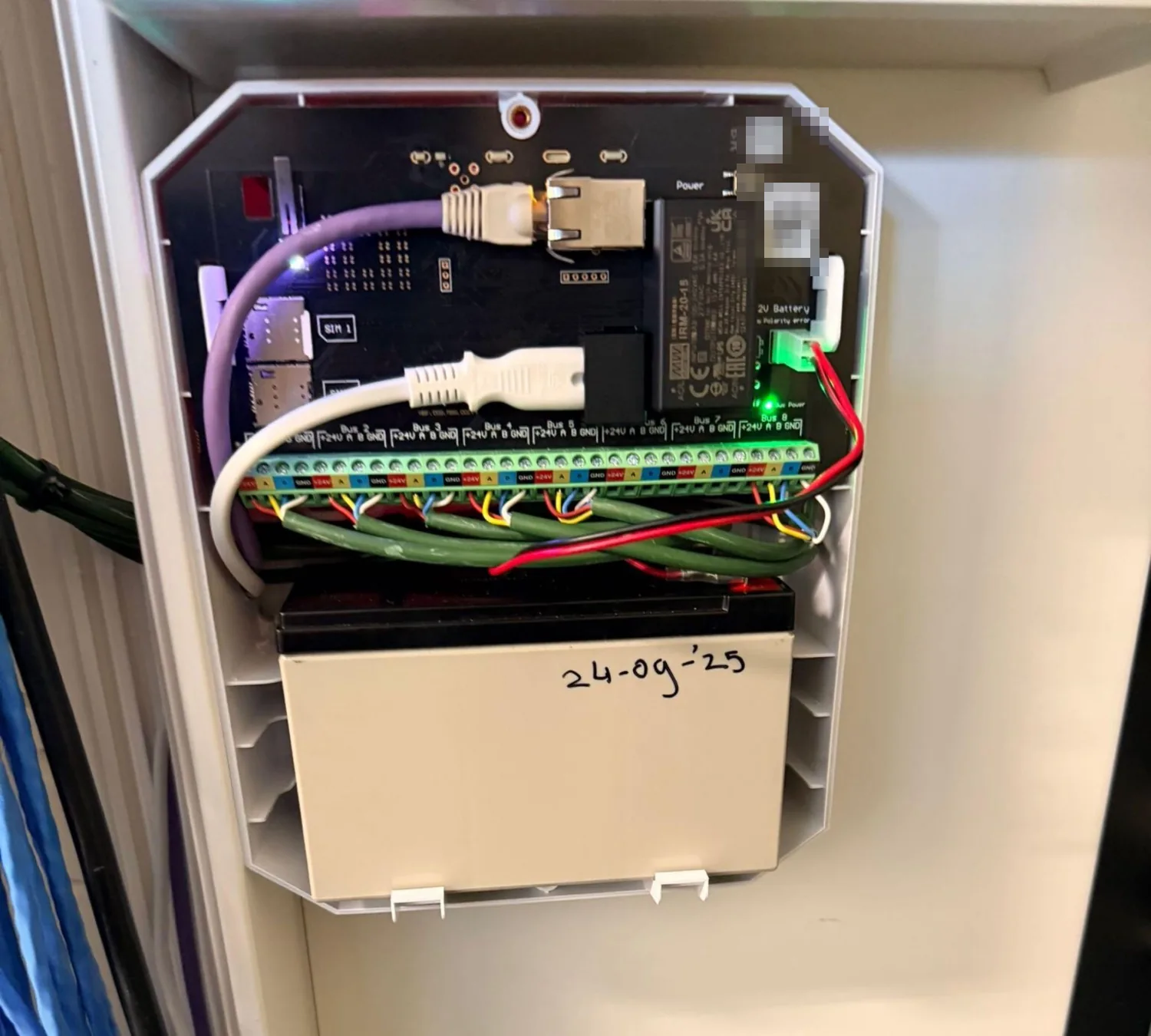 Open Ajax Hub Hybrid met aangesloten Fibra-bussen en een accu met de datum erop, op een kantoor in Amsterdam