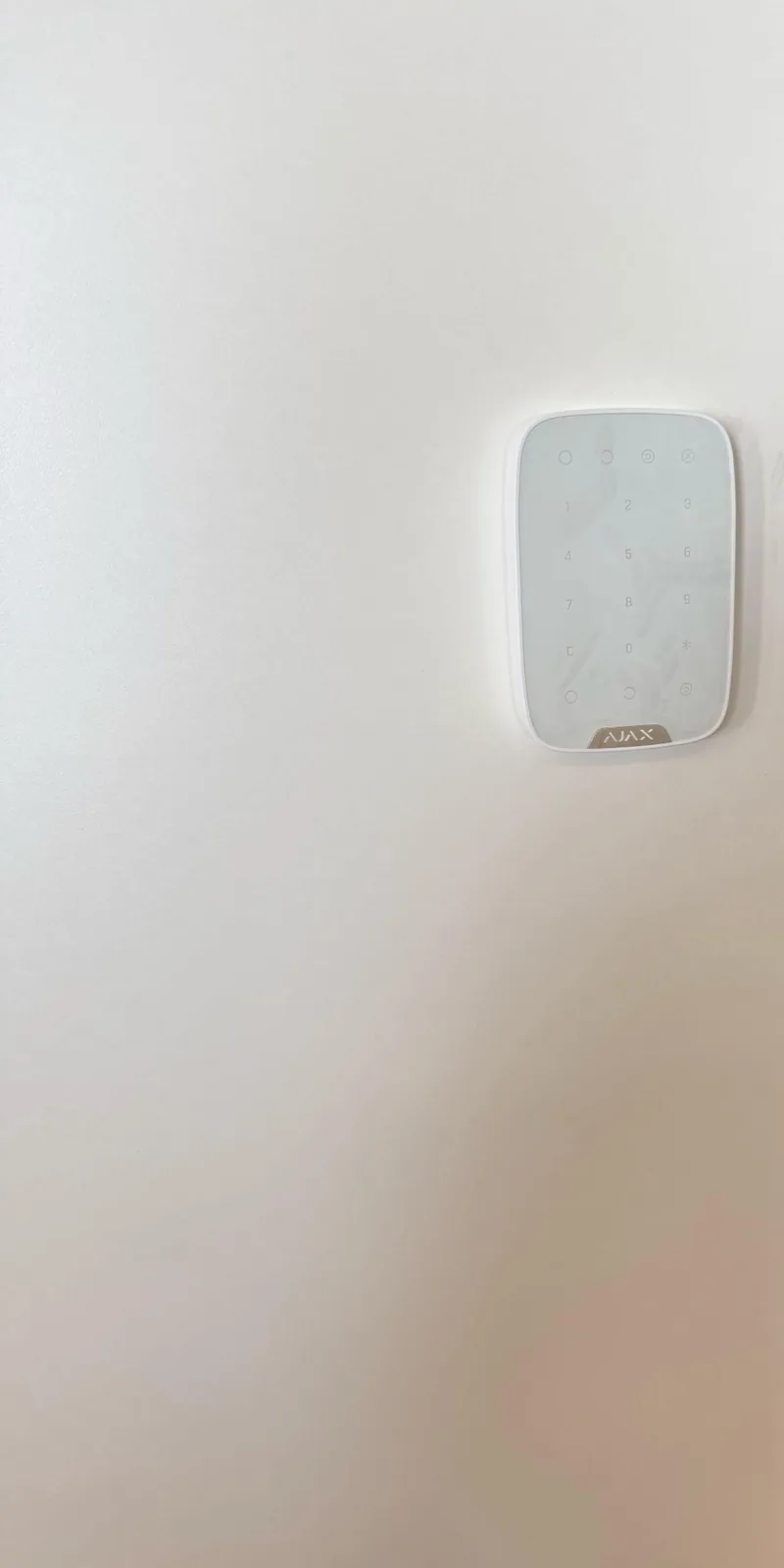 Witte Ajax Superior KeyPad Fibra op een witte wand naast de serverruimte
