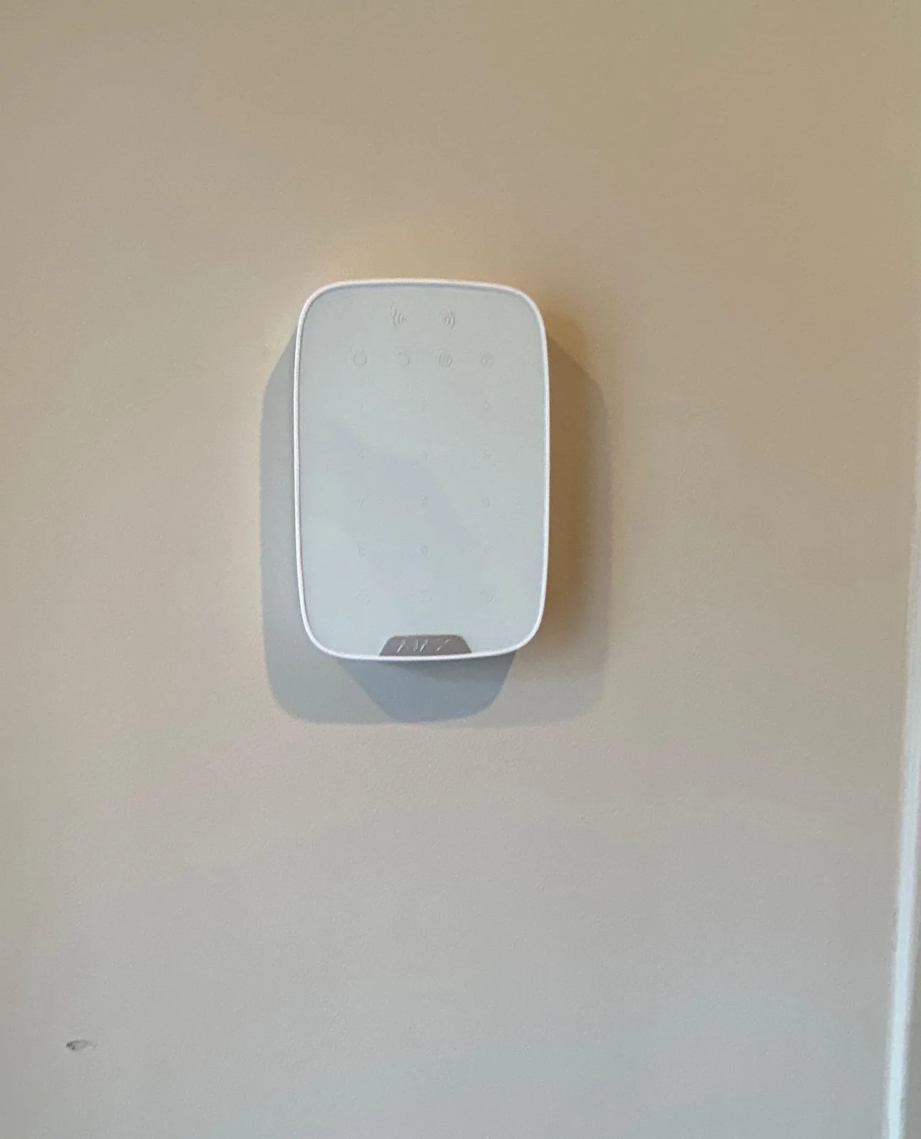 Wit Ajax-bediendeel Superior KeyPad G3 Plus met aanraaktoetsen, op ooghoogte aan een lichte wand in de woning