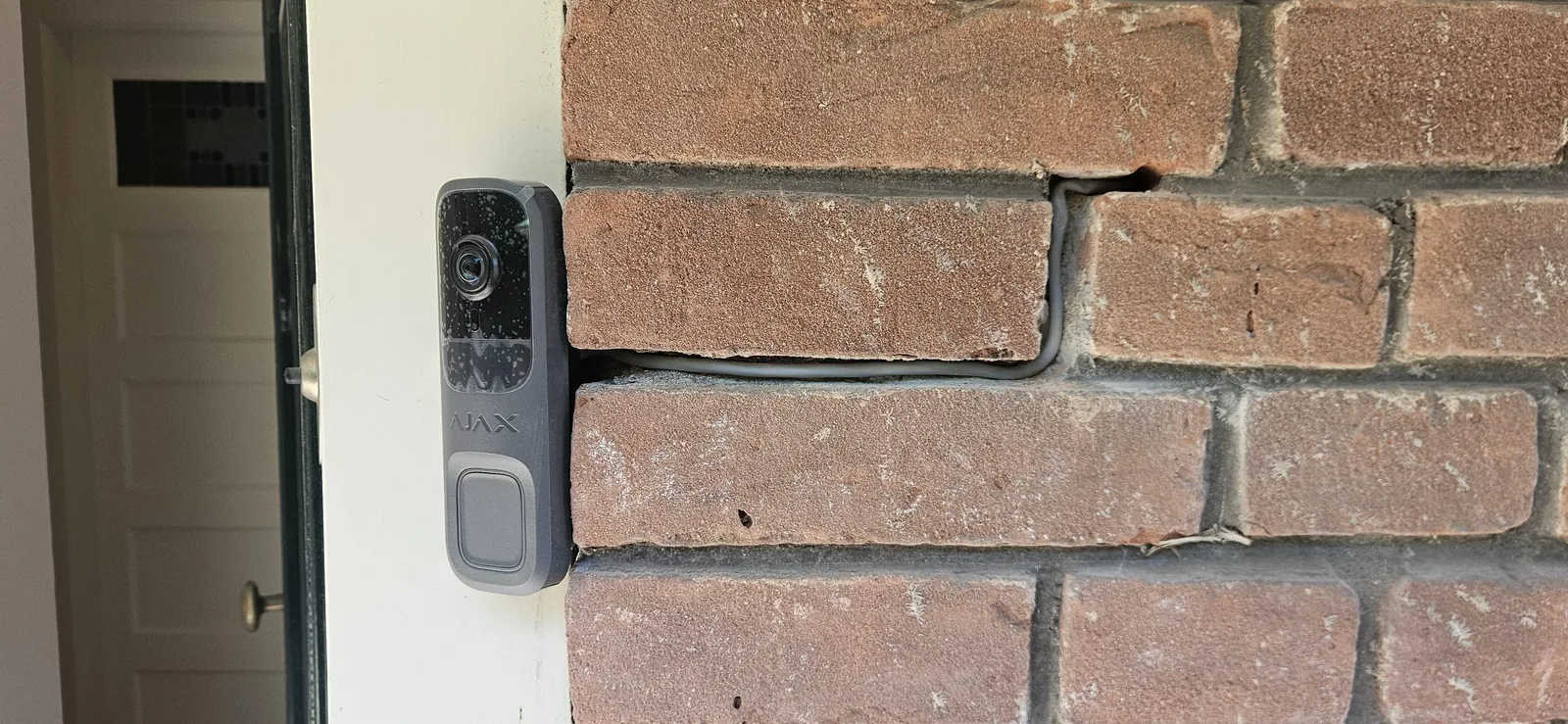 Ajax-videodeurbel naast de voordeur, met de kabel weggewerkt in de voeg, bij een woning in Zeist