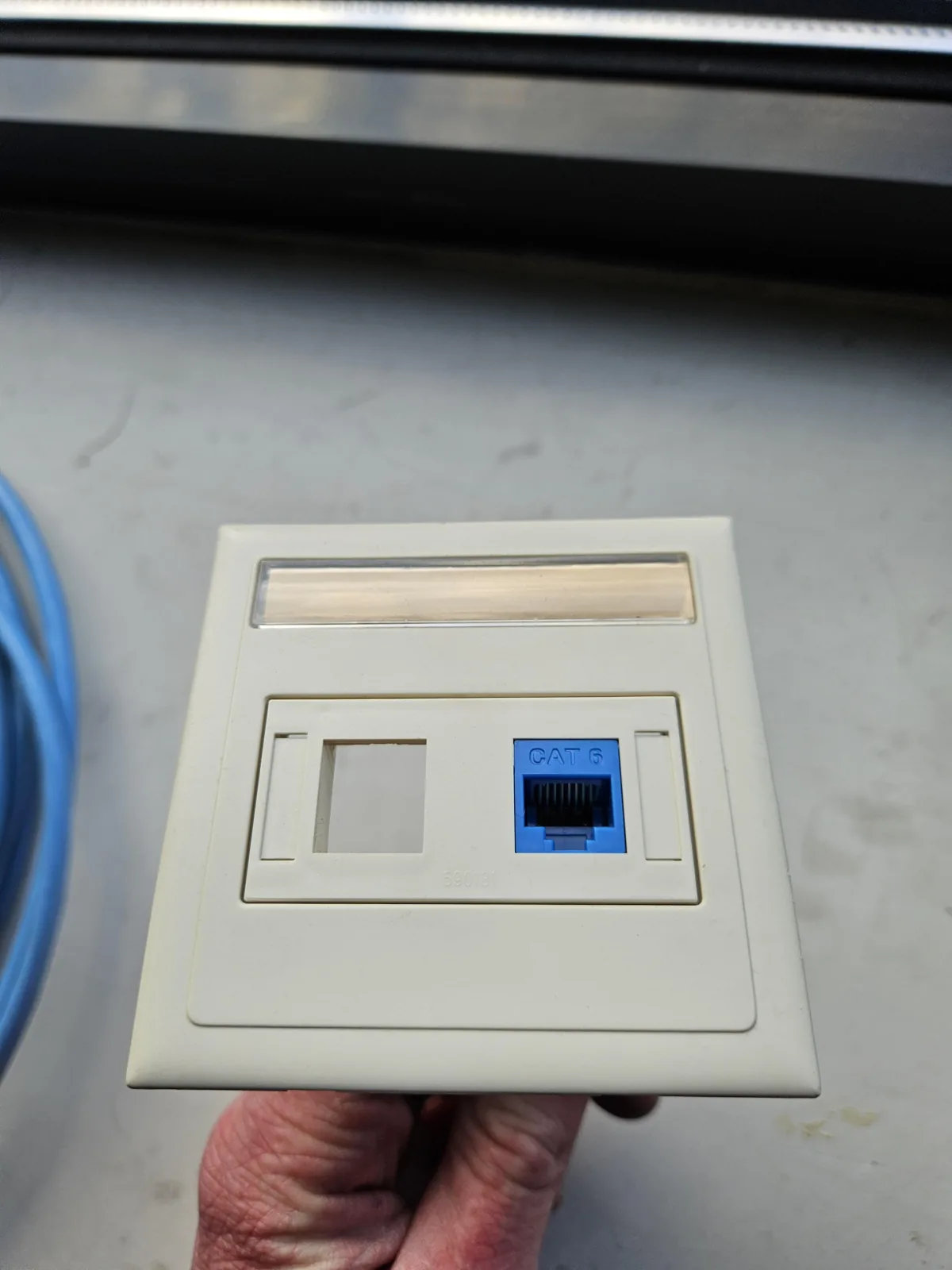 Bestaande crèmekleurige faceplate met een blauwe keystone, waar de nieuwe keystone in moest passen