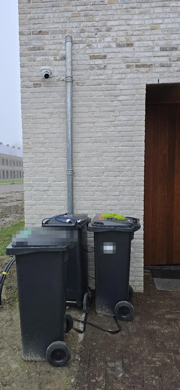Witte Dahua-turret hoog op de zijgevel van een nieuwbouwwoning in Cruquius, naast de regenpijp en boven de containers