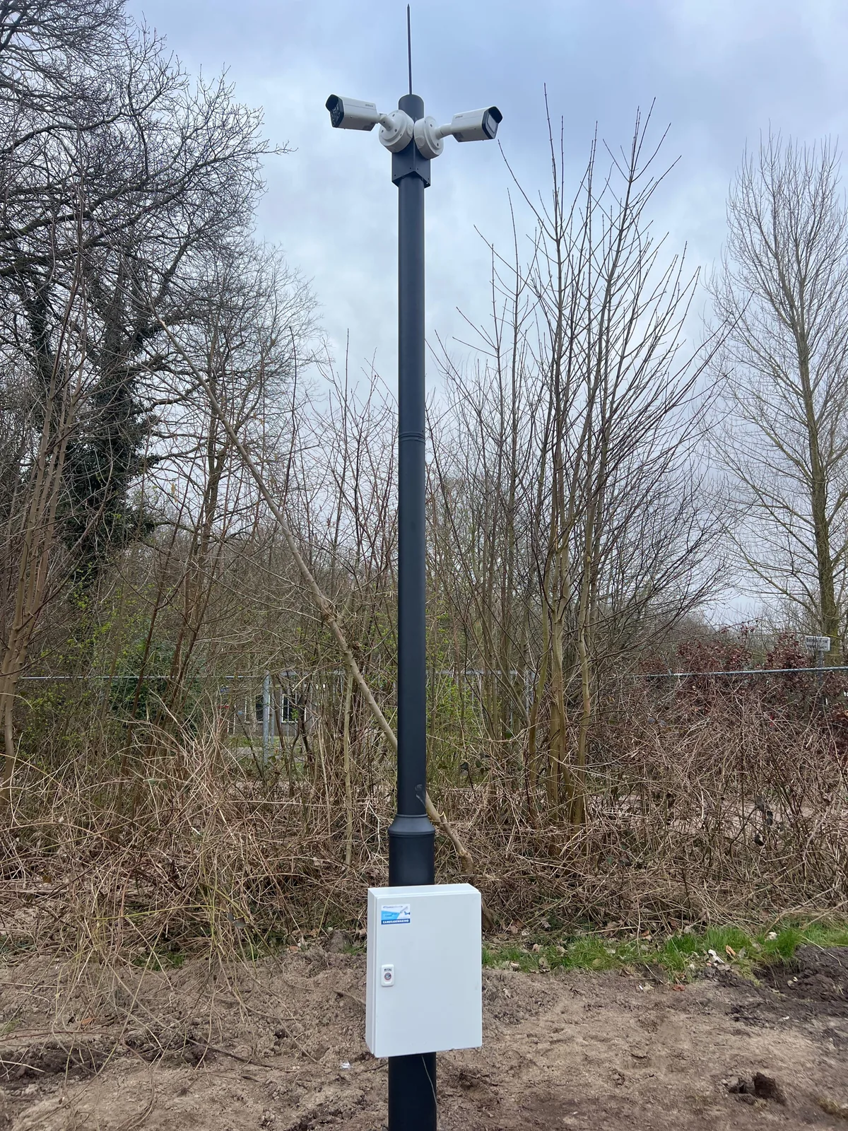 Zwarte camerapaal met bovenin twee Dahua-bulletcamera's en onderaan een witte aansluitkast