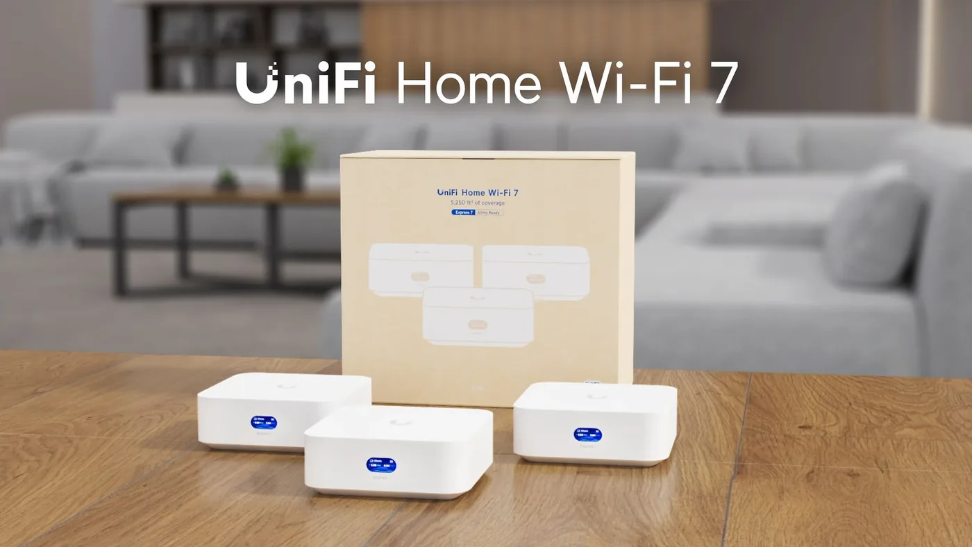 Drie witte UniFi Express 7-kastjes met de doos van UniFi Home WiFi 7 op een tafel in een woonkamer