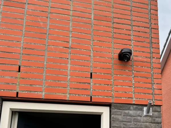 Zwarte Dahua-camera op de gevel boven de voordeur van een hoekwoning in Purmerend