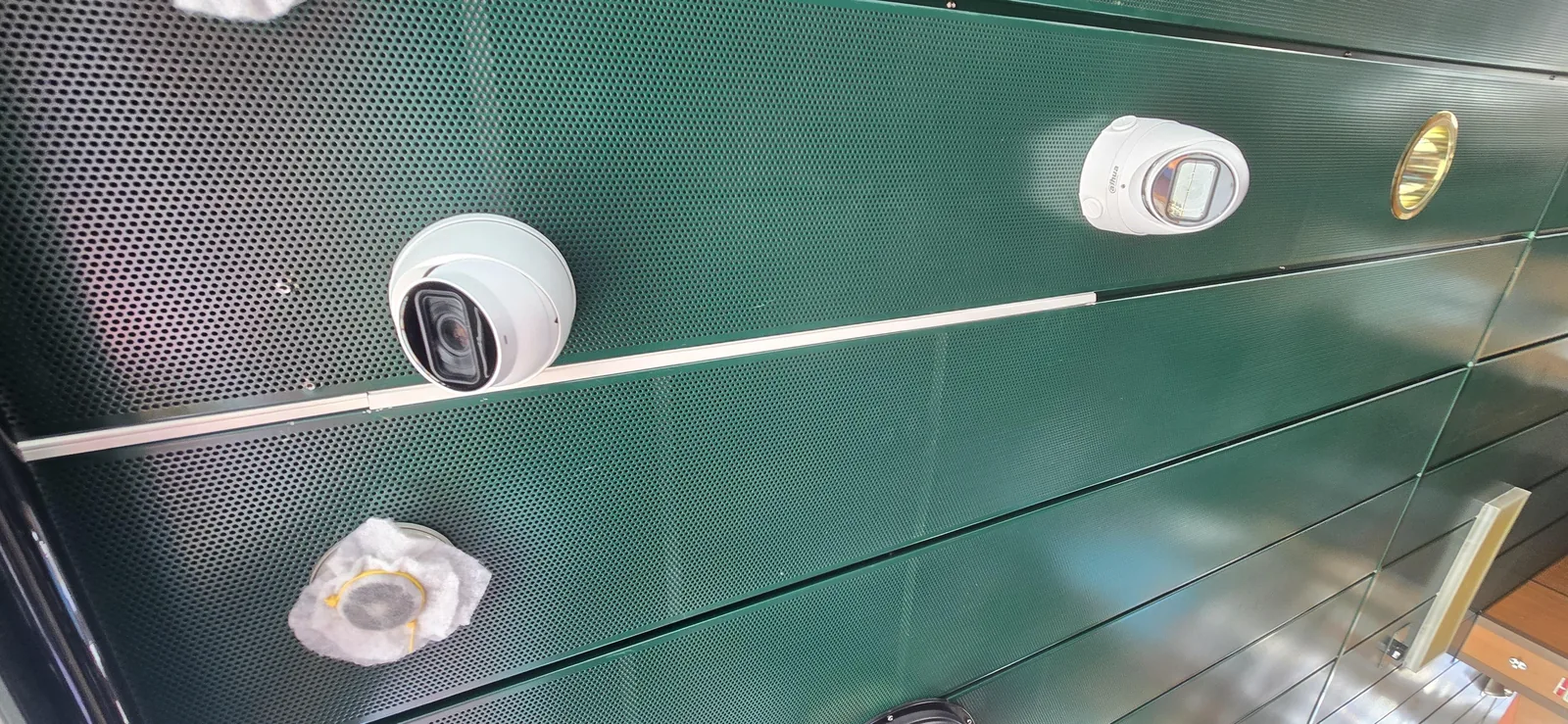 Witte Dahua-camera met motorzoom tegen het groene geperforeerde plafond van de stuurhut van een containerschip