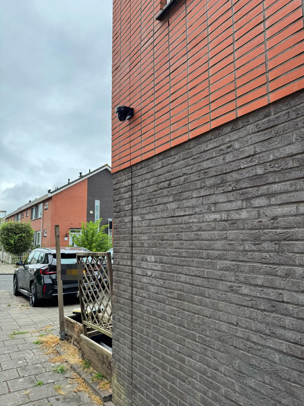 Zwarte Dahua-camera hoog op de zijgevel van een hoekwoning in Purmerend, boven de steeg