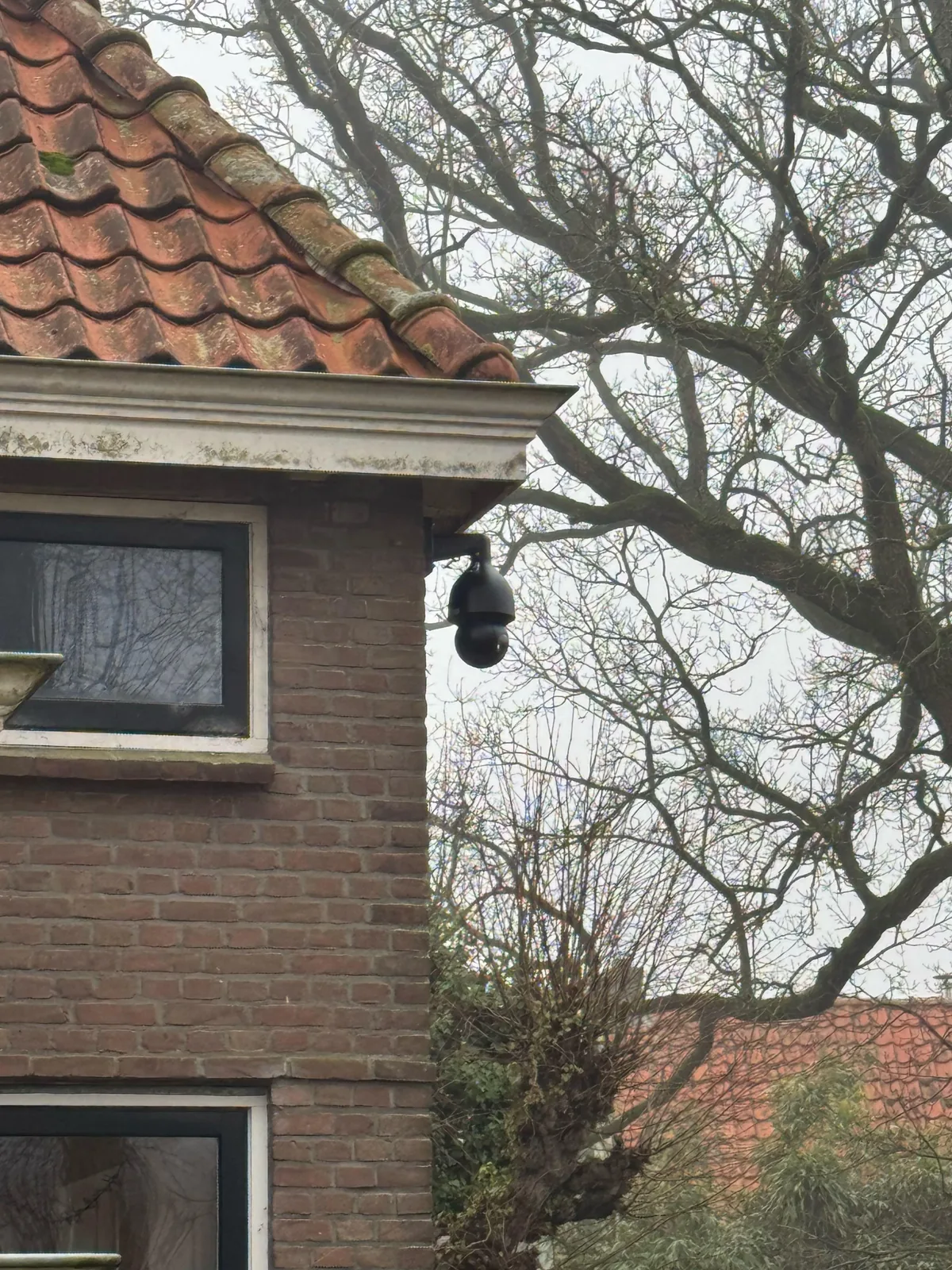 Zwarte Dahua PTZ-camera van 8 MP aan een muurbeugel op de hoek van een bakstenen woning in Amstelveen