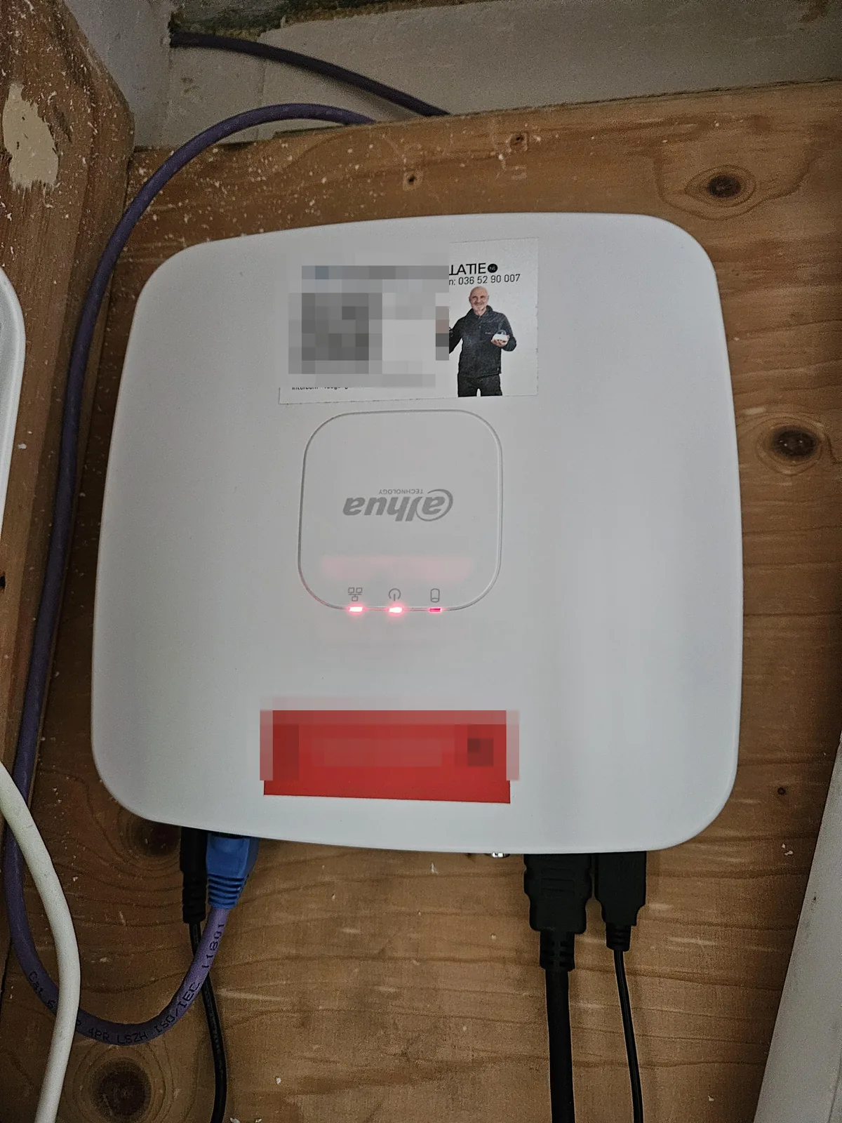 Witte Dahua-recorder op de houten plaat in de meterkast, met de sticker van CameraInstallatie.nl