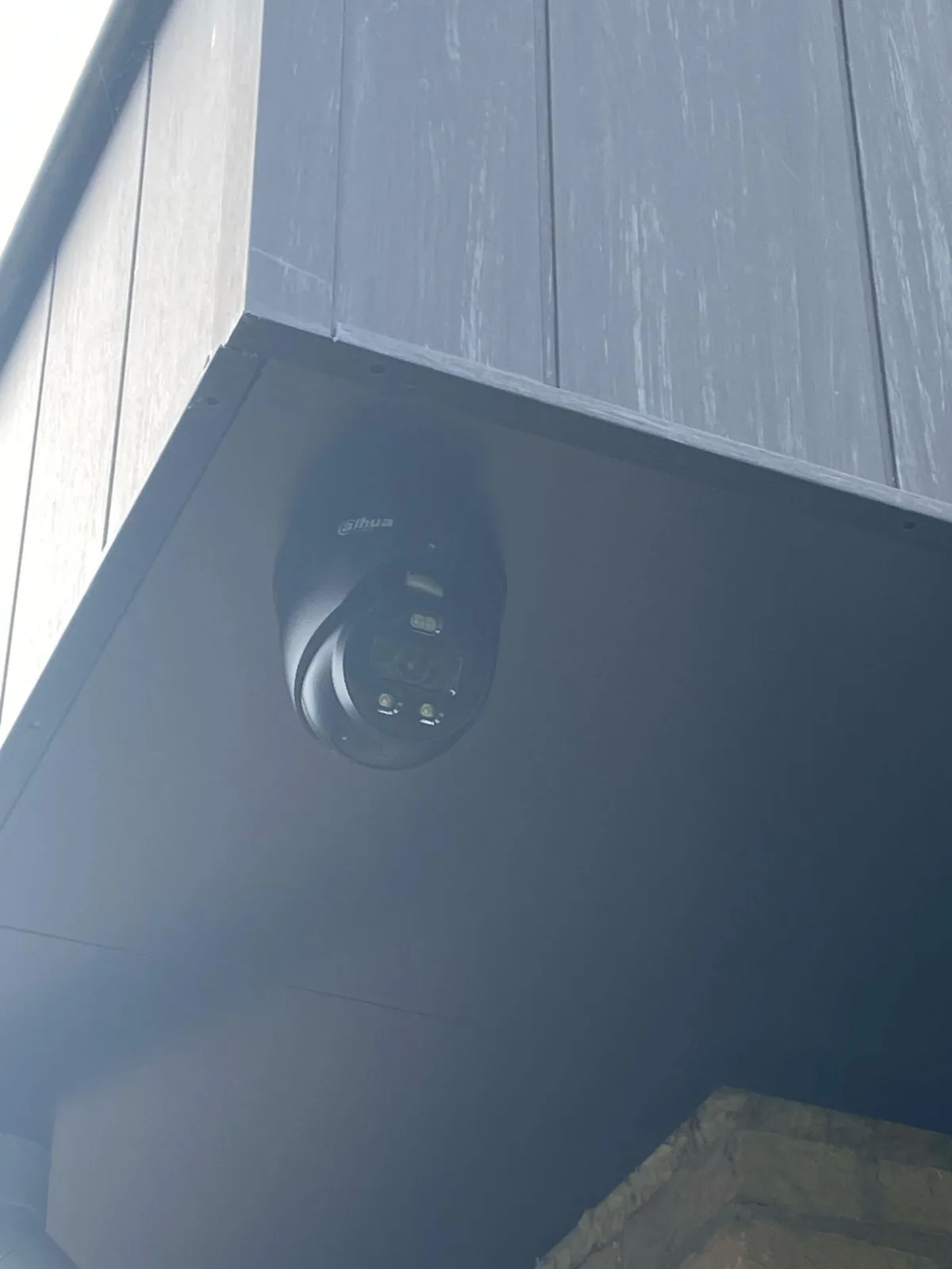 Zwarte Dahua TiOC-camera van dichtbij onder het overstek, met de lampen rond de lens