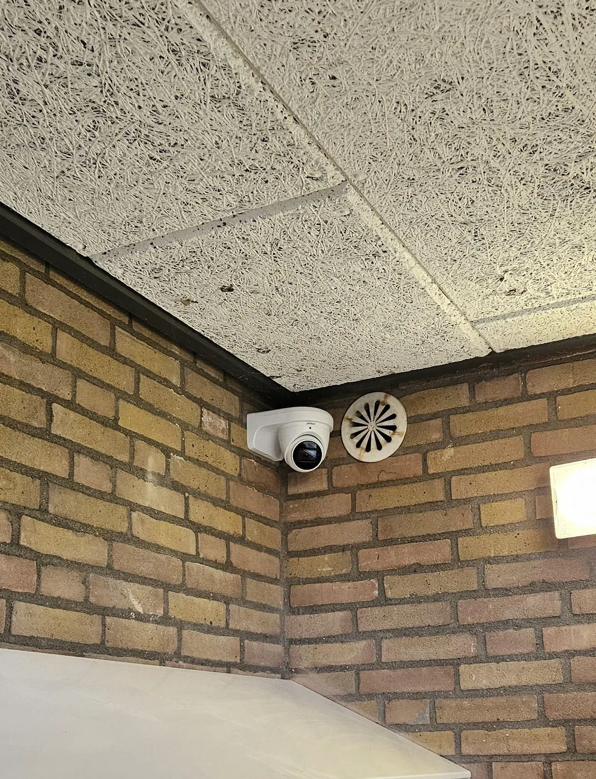 Witte camera hoog in de hoek van een entreehal, boven de brievenbussen, bij een VvE in Zoetermeer