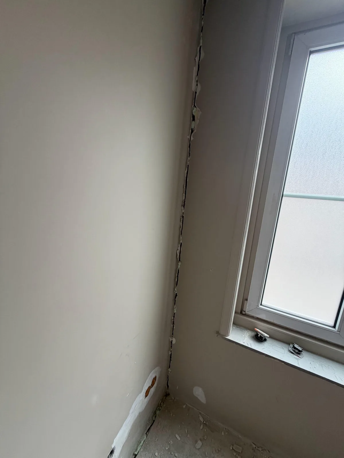 Gefreesde sleuf in de hoek van een kamer bij het raam, dichtgezet met schuim